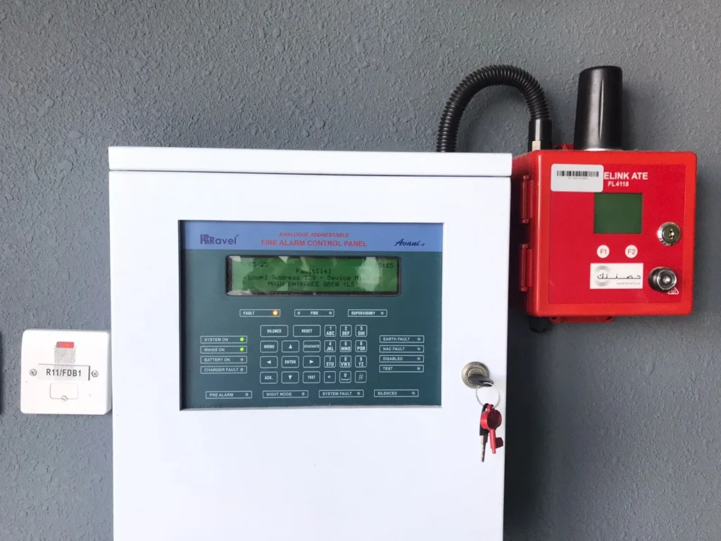 Essential components of fire alarm systems including detectors, a control panel, and notification devices displayed on a workbench
